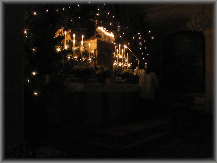 ministrant zapaluje svíce na hlavním oltáři před půlnoční bohoslužbou